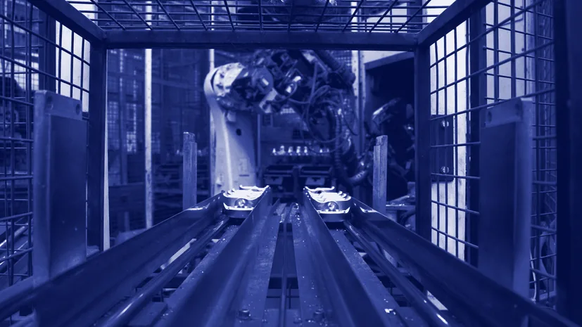 A robot arm working at a conveyor behind a safety cage